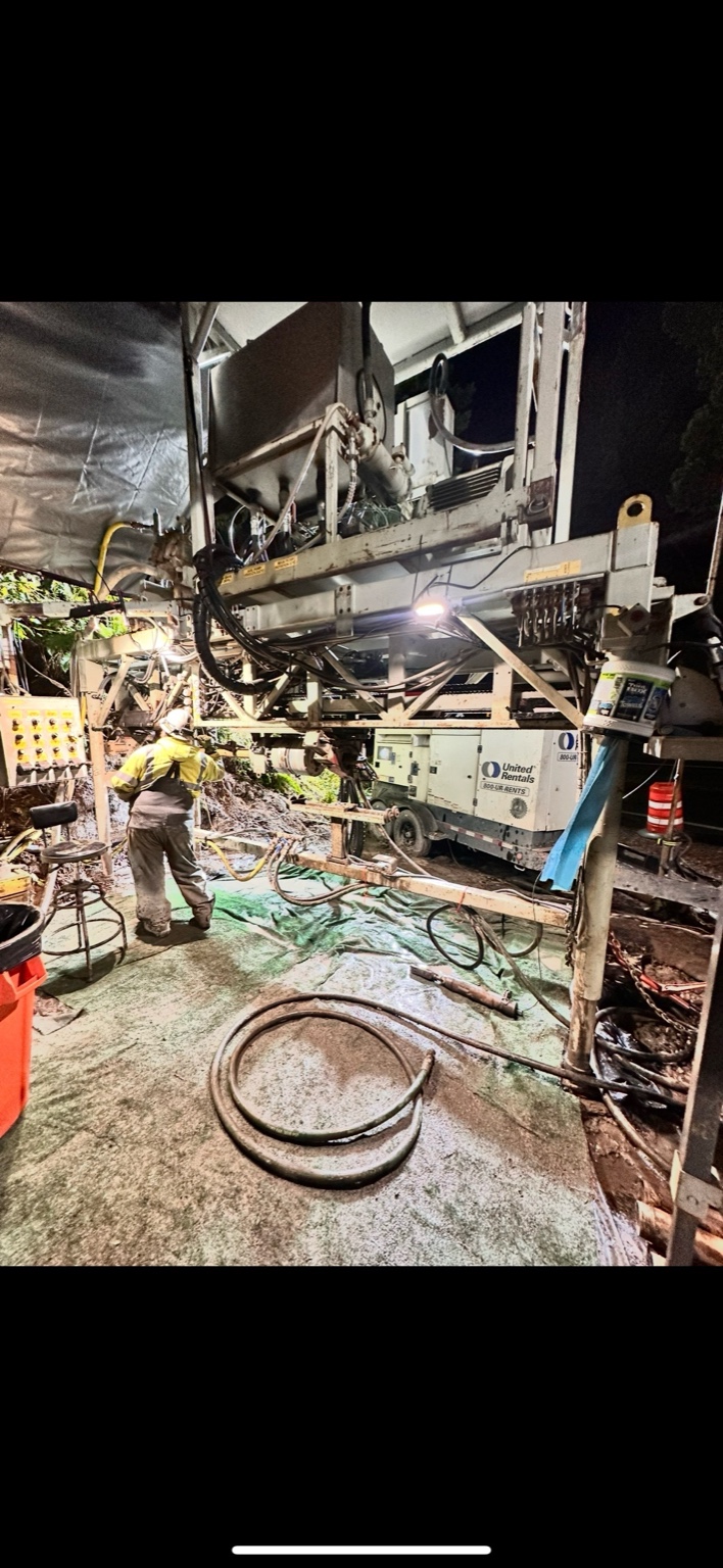 Night drill rig platform surrounded by cables, generator, and hydraulic lines